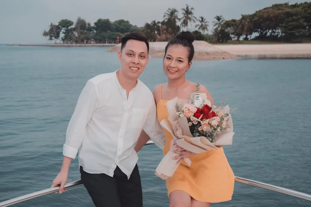 Couple celebrating with a bouquet on a yacht in Singapore