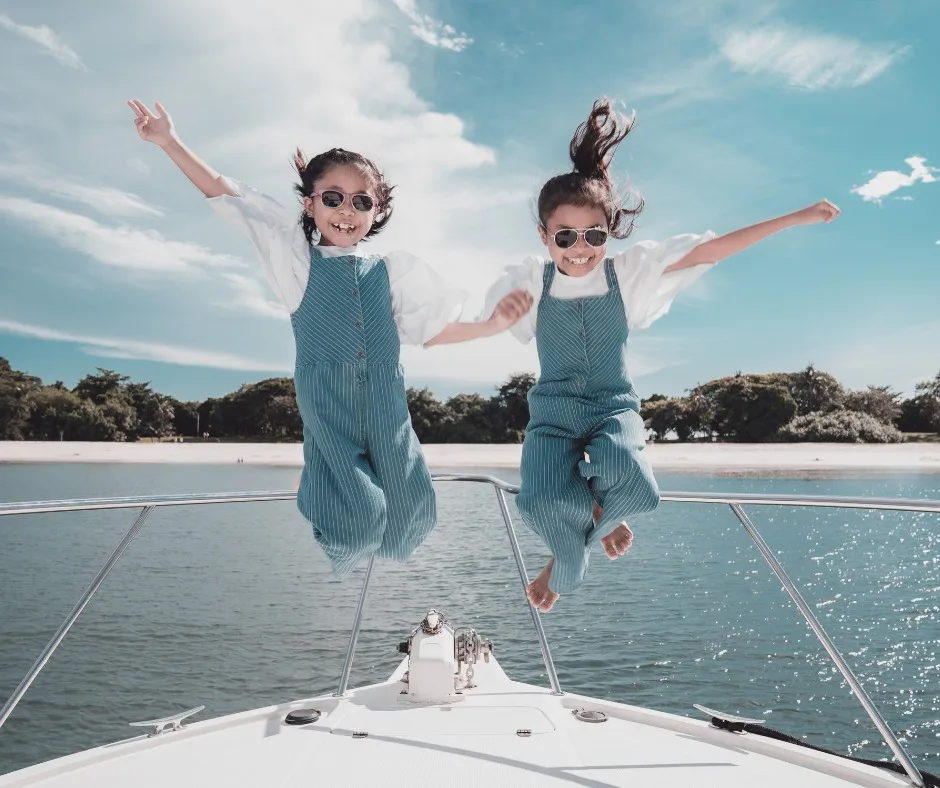 Kids jumping for joy on the bow of a Sea Friends yacht