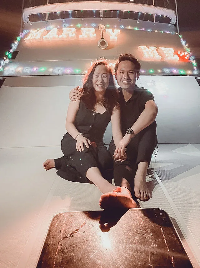 Engaged couple under the Marry Me lights